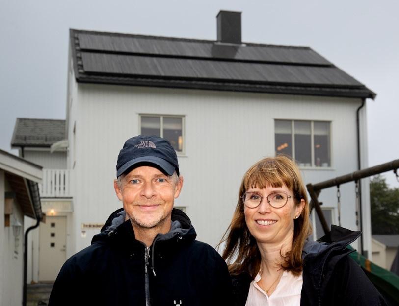Par smiler foran hus med solcelleanlegg